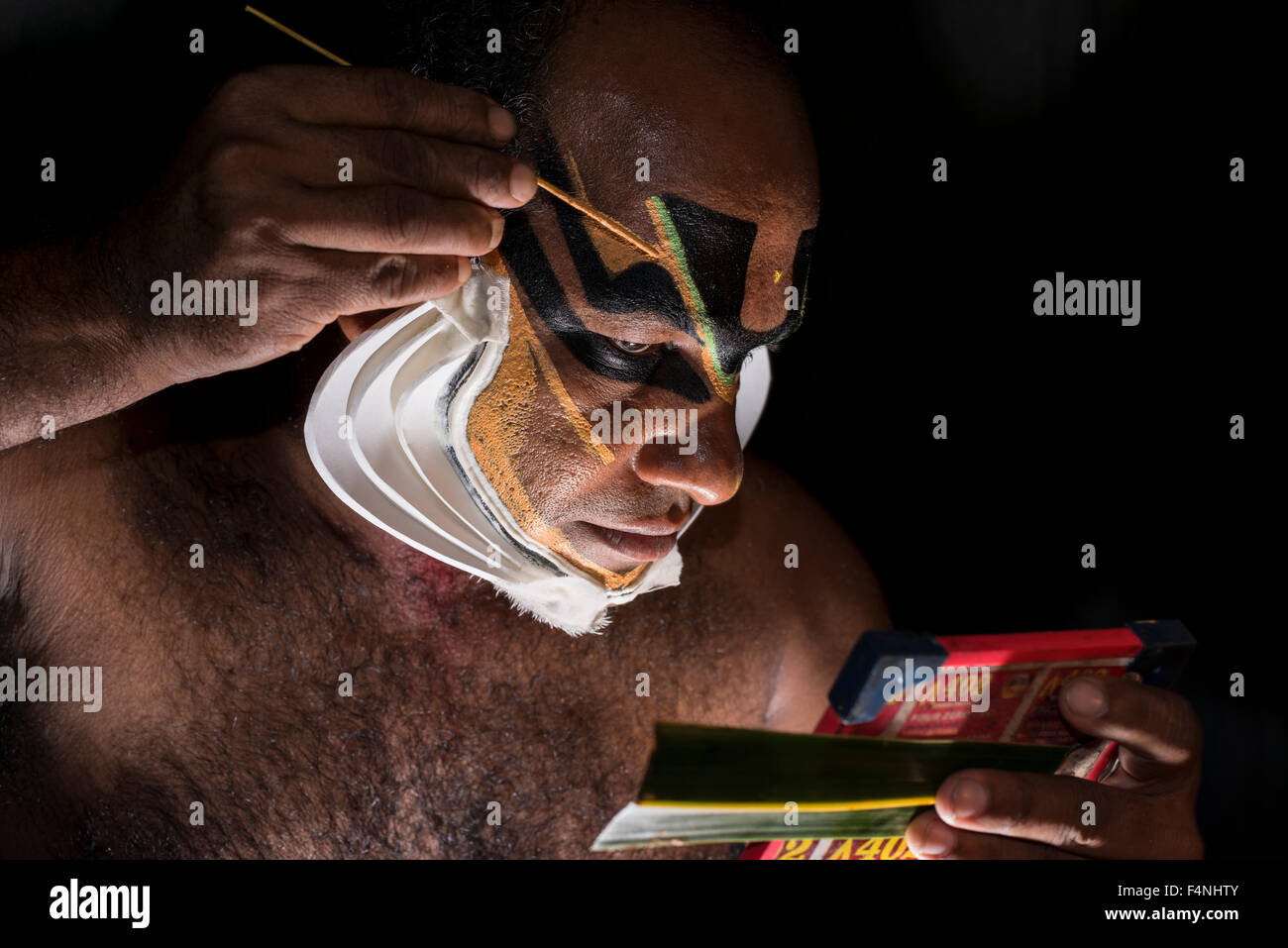 Un artista katakali è applicare il make up del carattere di Shiva per il gioco dhecheyagam Foto Stock