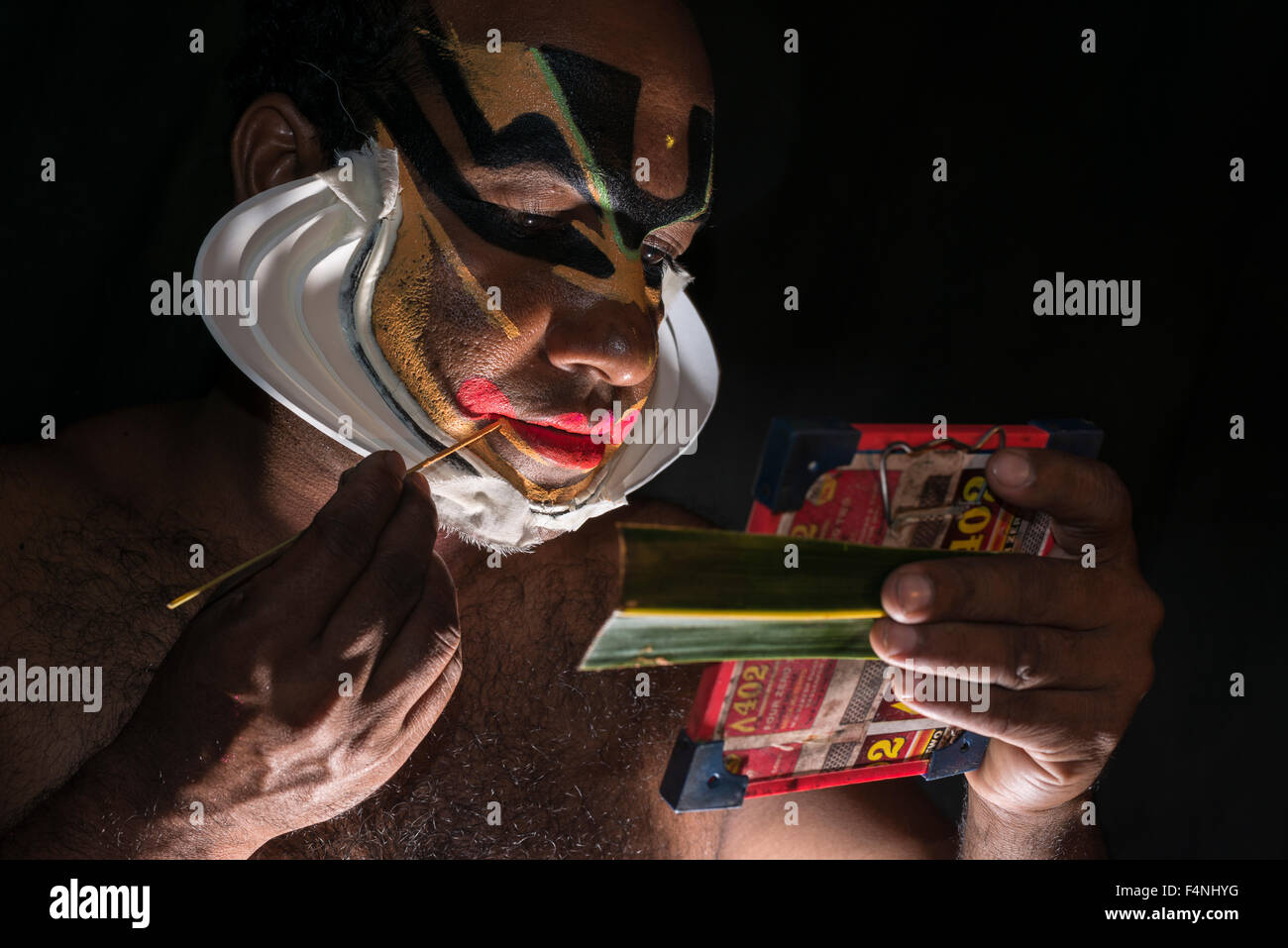 Un artista katakali è applicare il make up del carattere di Shiva per il gioco dhecheyagam Foto Stock