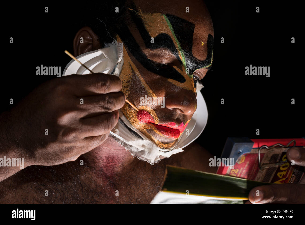 Un artista katakali è applicare il make up del carattere di Shiva per il gioco dhecheyagam Foto Stock