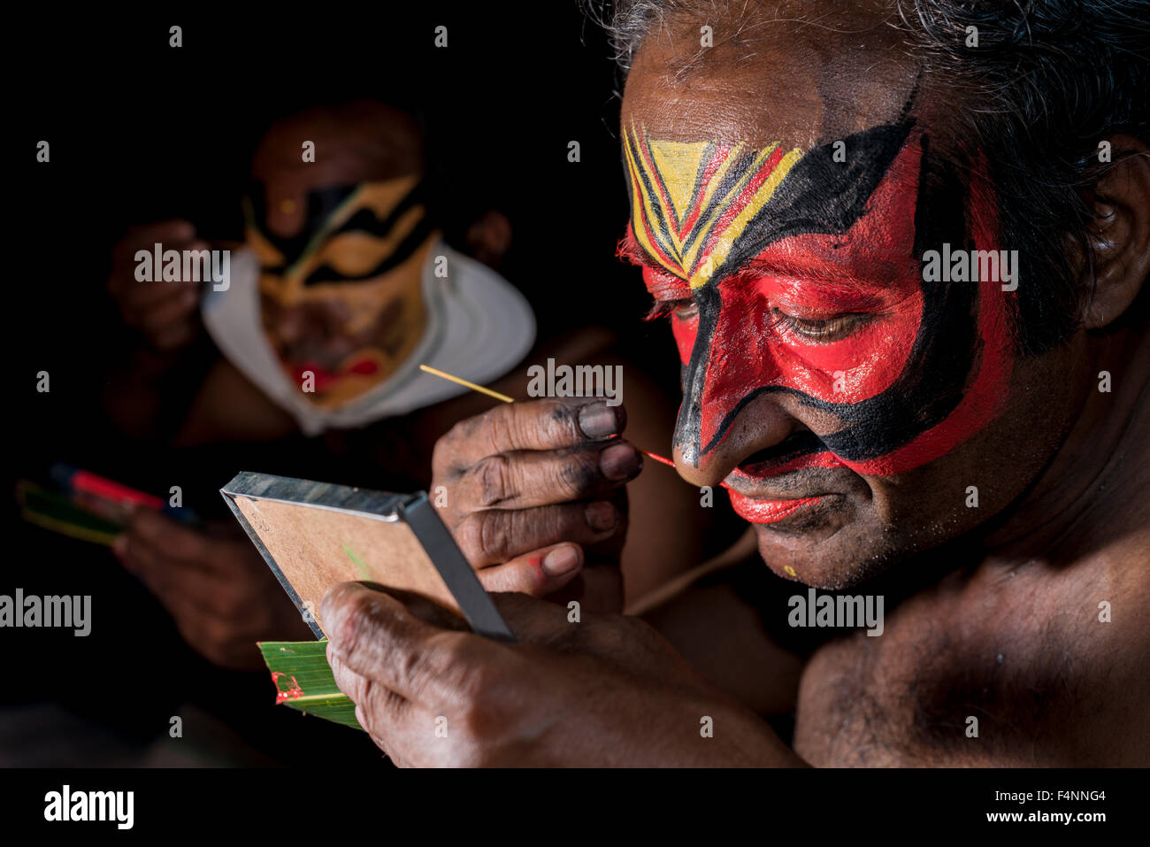 Un artista katakali è applicare il make up del carattere virabhatra per il gioco dhecheyagam Foto Stock