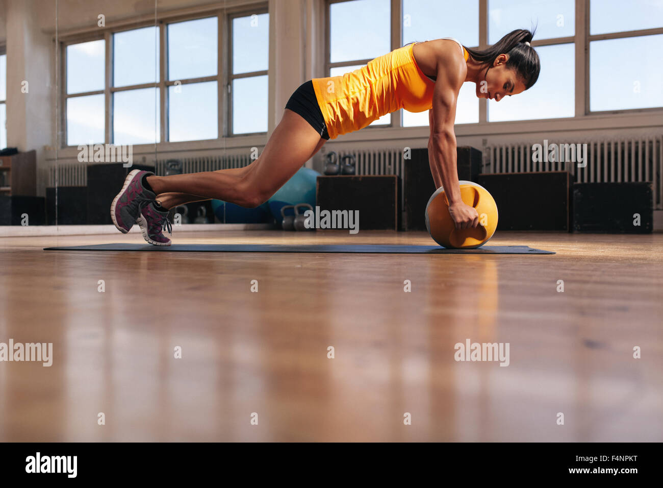 Montare il giovane atleta femminile che lavora fuori sul suo core muscoli. Donna muscolare esercitando sul tappetino fitness facendo spingere ups con kettlebel Foto Stock