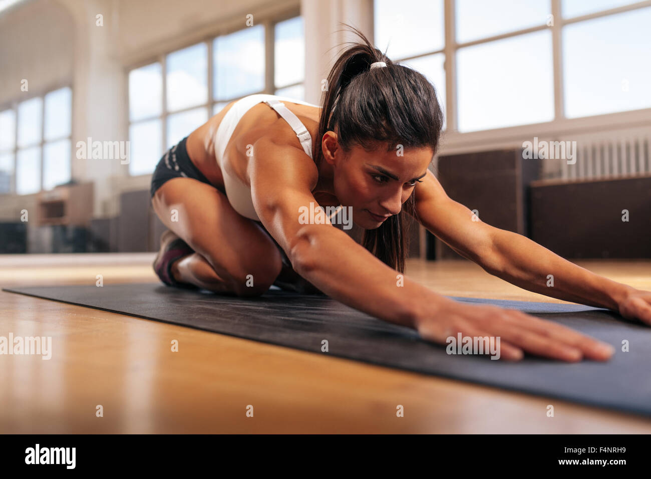 Giovane donna muscolare facendo stretching allenamento sul tappetino fitness. Eseguire femmina yoga presso la palestra. Foto Stock