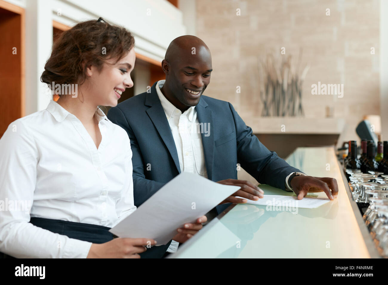 Felice di giovani uomini di affari che la lettura di alcuni documenti e sorridente. I dirigenti seduti al cafe con report di business. Foto Stock