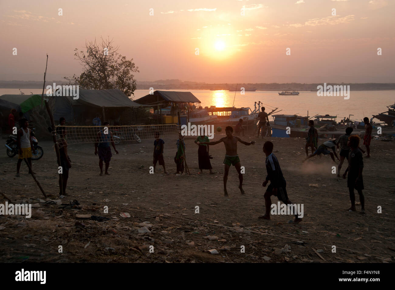 Gli uomini birmani giocare una palla di gioco sulle rive del fiume Ayarwaddy come il sole tramonta in Myanmar Mandalay Foto Stock