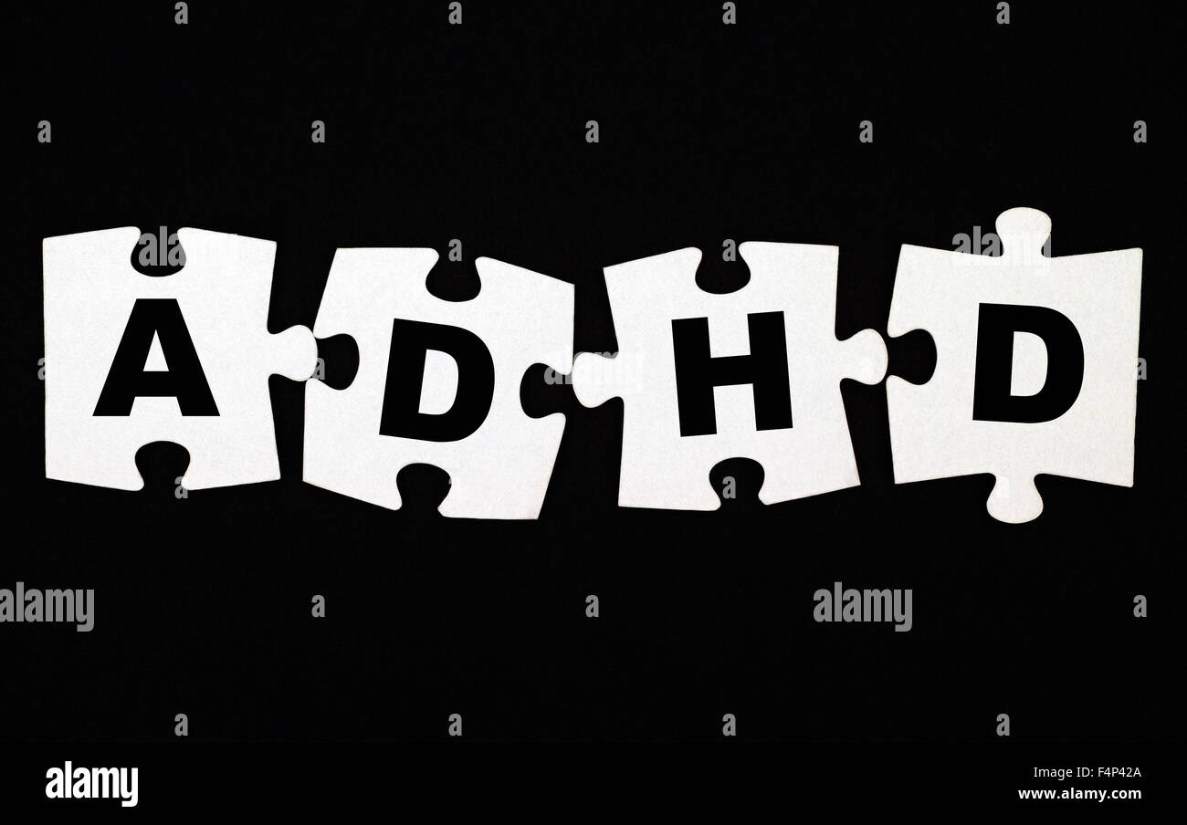Quattro pezzi di un puzzle con lettere ADHD su sfondo nero. L' ADHD è disturbo da deficit di attenzione e iperattività. Foto Stock