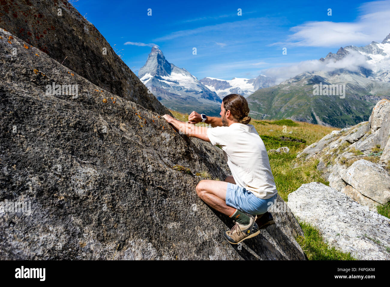Scalatore utilizza il suo smartwatch su un masso sotto il famoso Cervino picco. Luglio, 2015. Il Cervino, Svizzera. Foto Stock