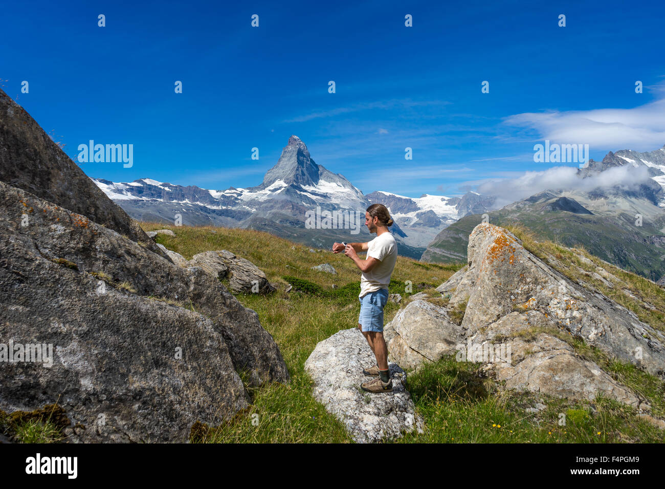 Trekker utilizza il suo smartwatch sotto il famoso picco Mattehorn. Luglio, 2015. Il Cervino, Svizzera. Foto Stock