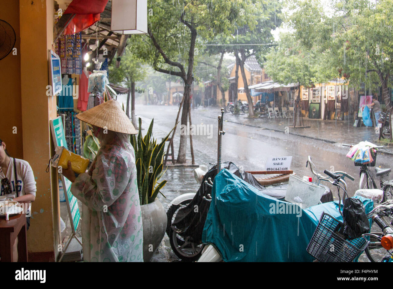 Antica città di Hoi An Vietnam lady vendere i Mac di pioggia a quelli alloggiati in un ristorante durante la tempesta. Foto Stock