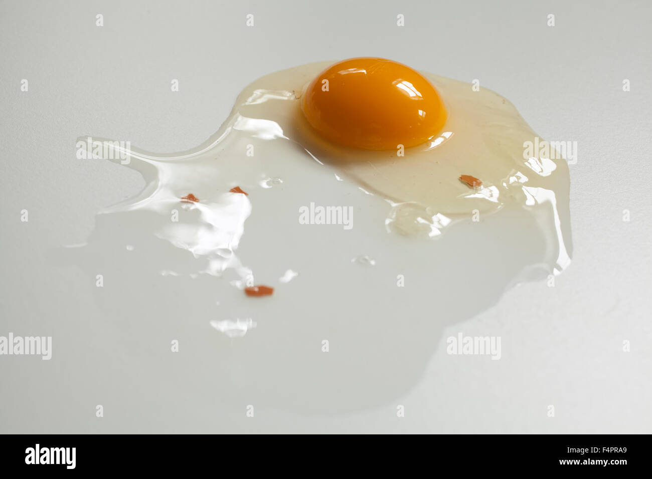 Rotture di greggio uovo marrone su sfondo bianco con piccoli frammenti di guscio. Foto Stock