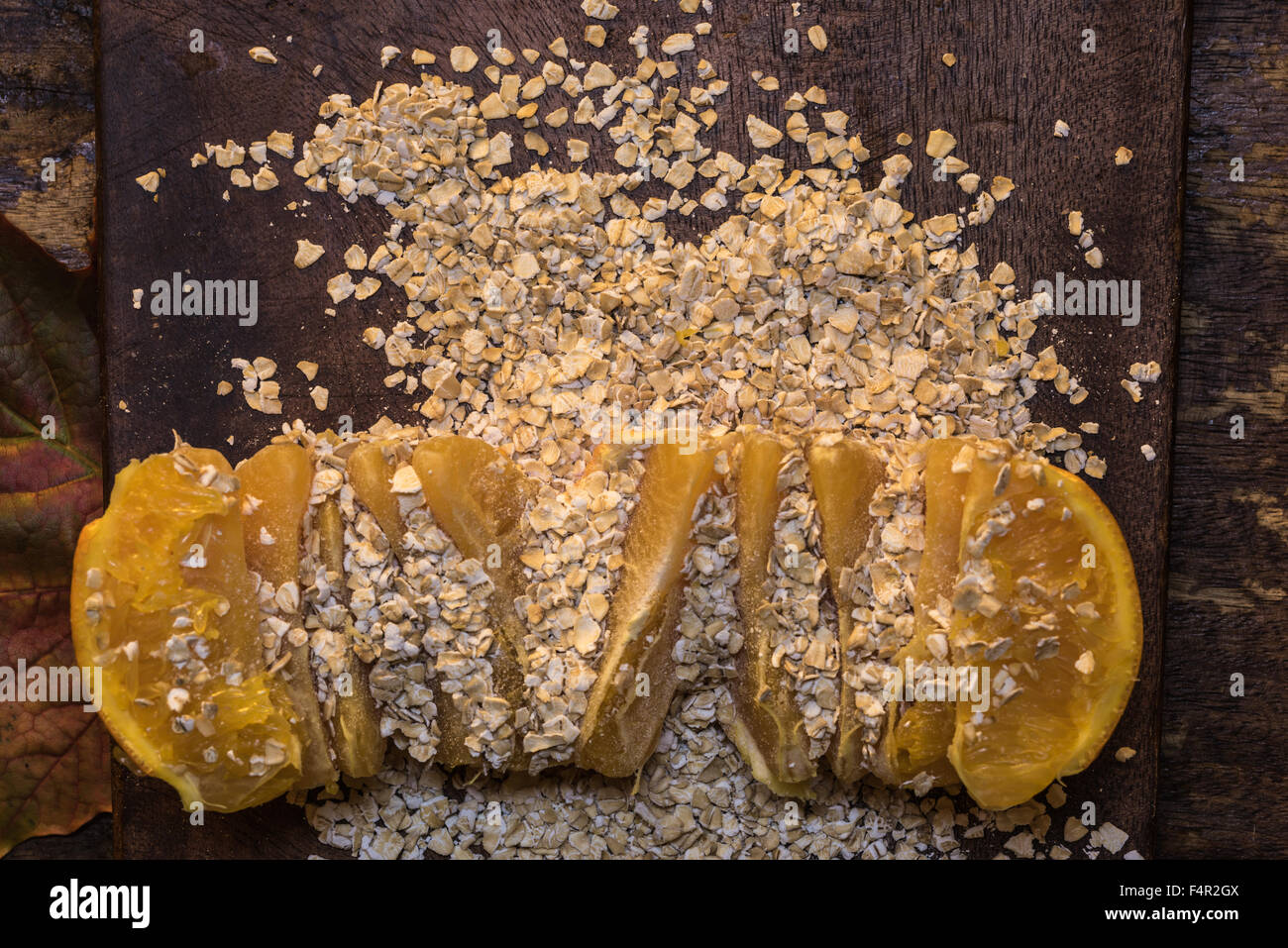 I fiocchi d'avena e arancio su un tagliere di legno - Cibo sinergia, cibo sano combinazione Foto Stock