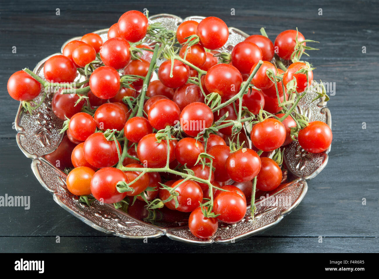 Freschi pomodori ciliegia in una ciotola di legno scuro tabella Foto Stock