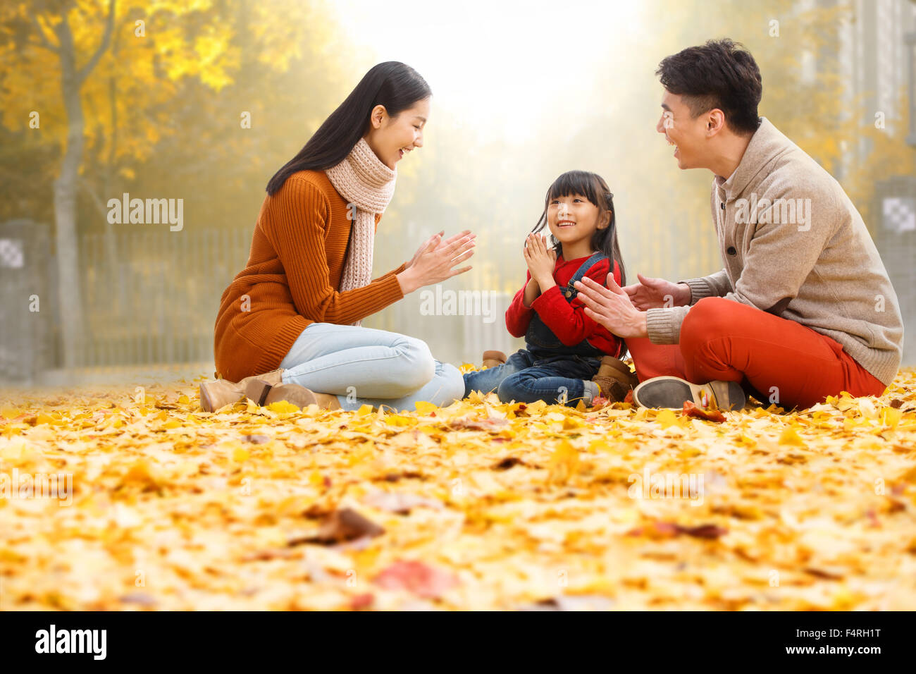 Famiglie felici sedersi sulle foglie e giocare. Foto Stock