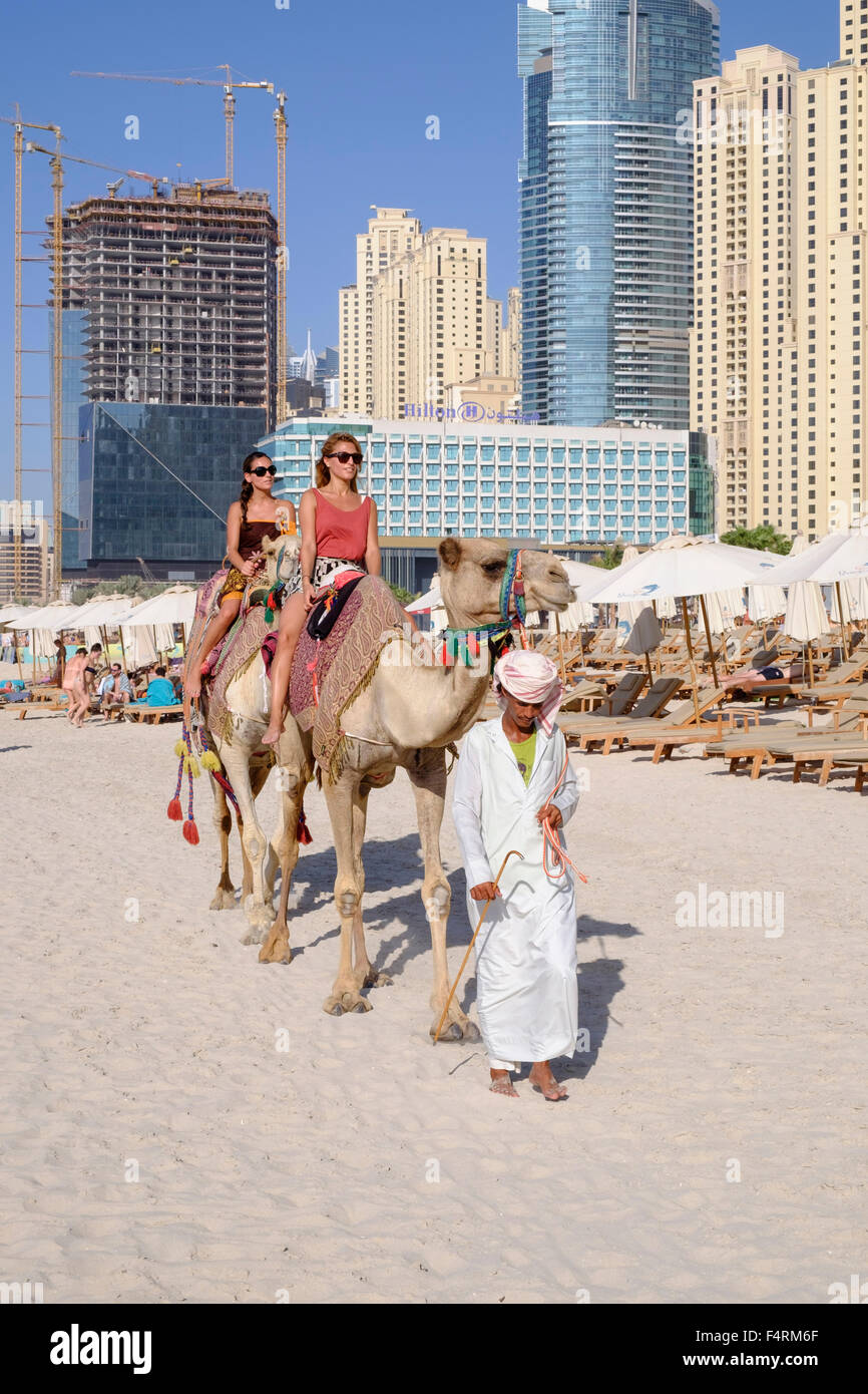 I turisti a cavallo cammello sulla spiaggia a JBR Jumeirah Beach Residence in Marina District di Dubai Emirati Arabi Uniti Foto Stock