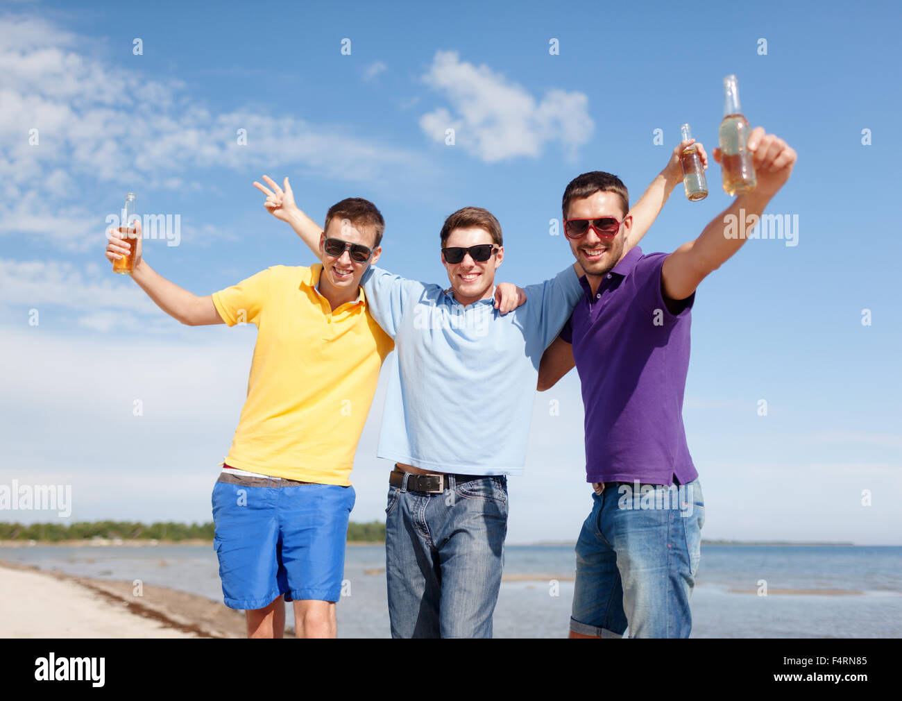 Happy amici con bottiglie di birra sulla spiaggia Foto Stock