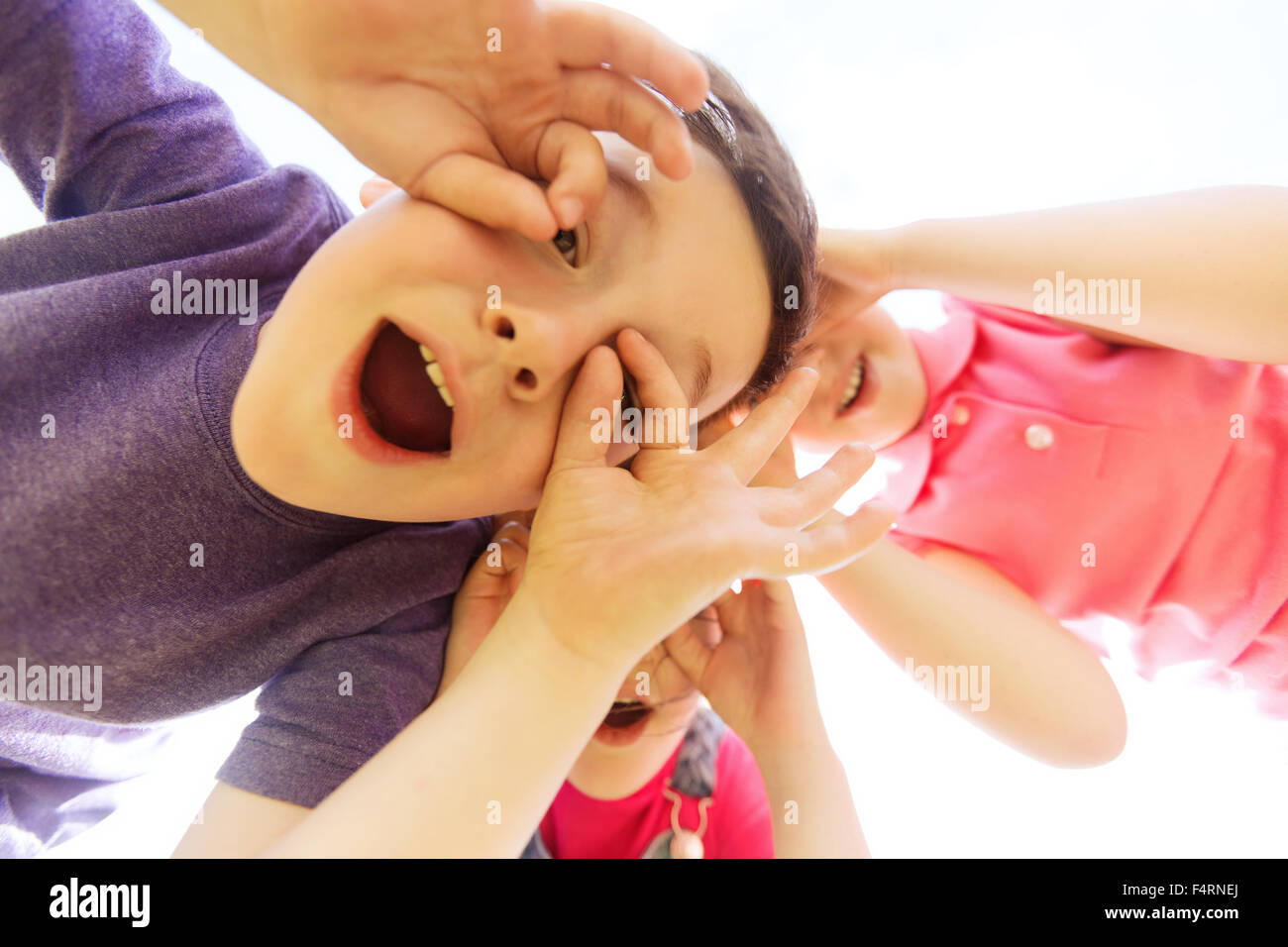 Gruppo di bambini divertendosi e rendendo i volti all'aperto Foto Stock