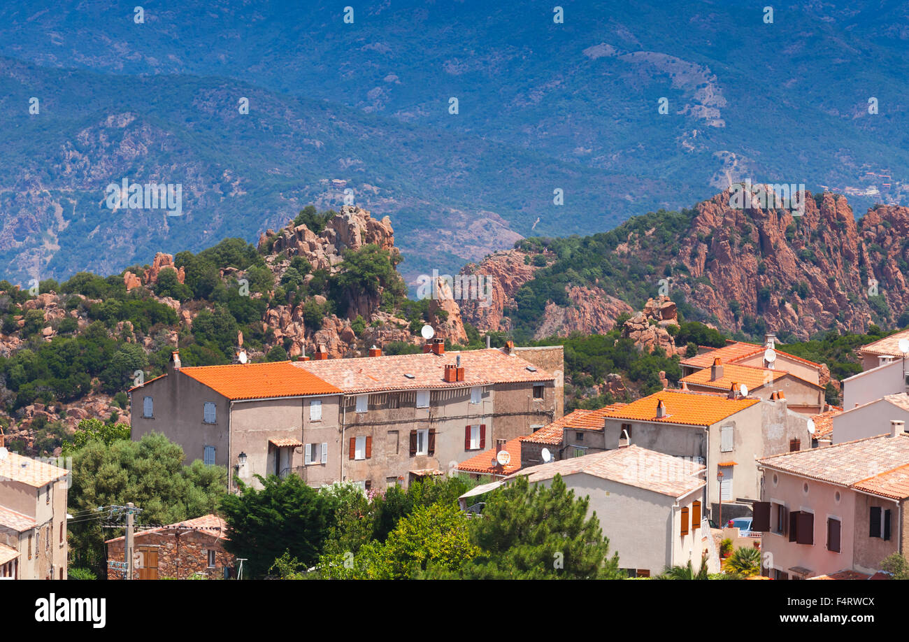 Piccolo villaggio corso cityscape, vecchie abitazioni con tetti in tegole rosse sulle montagne sullo sfondo. Piana, Sud Corsica, Francia Foto Stock