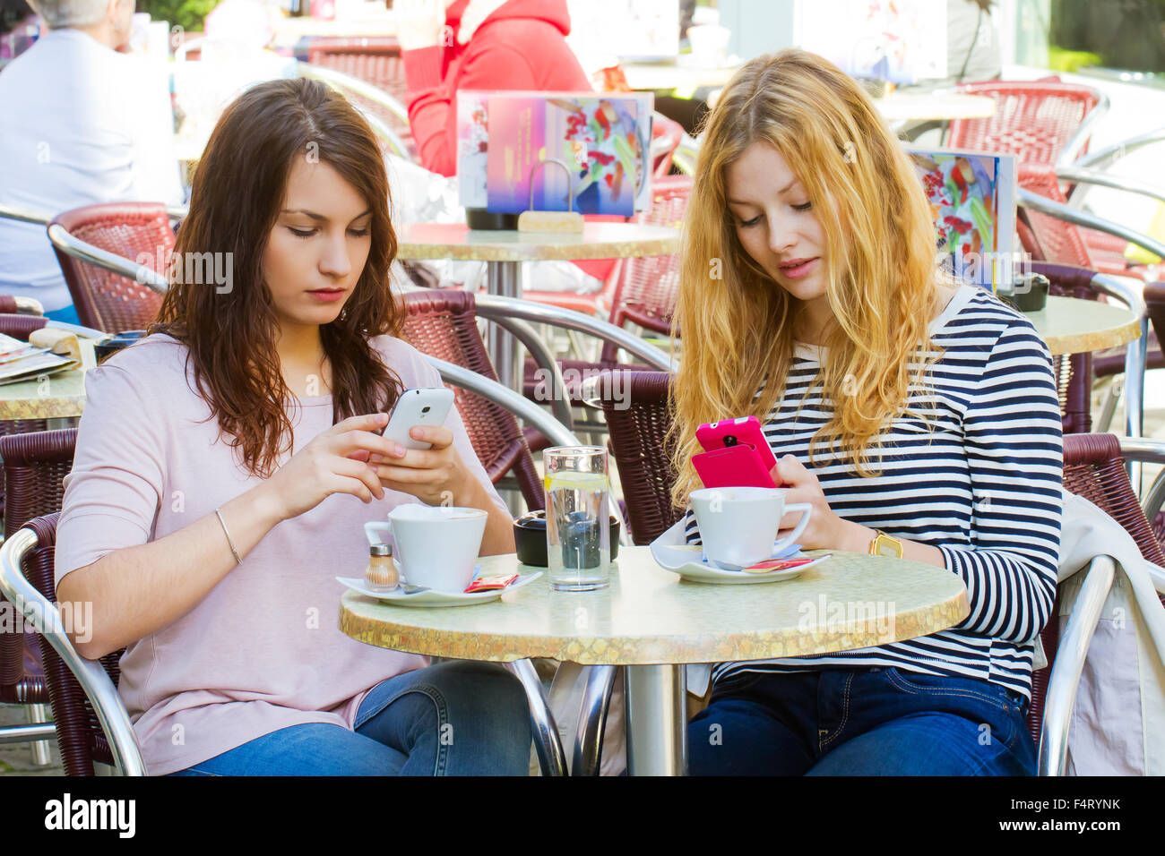 Due giovani donne con i loro nuovi telefoni intelligenti Foto Stock