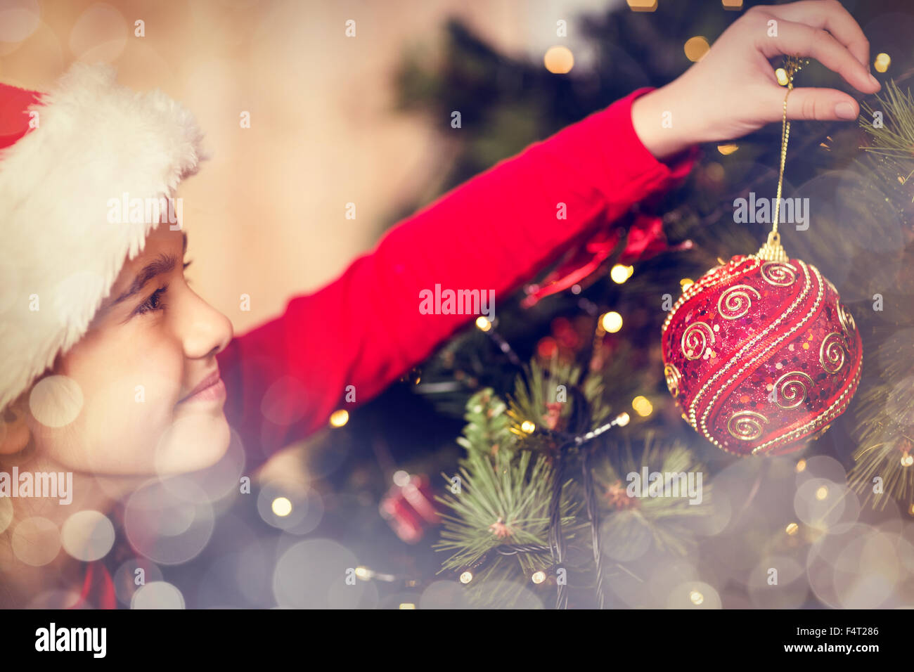Immagine composita di festosa bambina appesa una decorazione natalizia Foto Stock