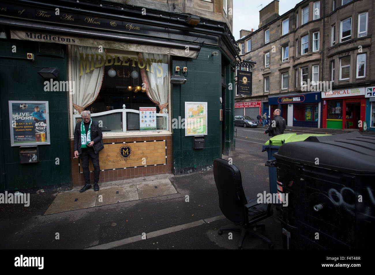 Una ventola home texting fuori da un bar in strada di Pasqua prima del campionato scozzese match tra Hibernian e visitatori Alloa Athletic. La squadra di casa ha vinto il gioco da 3-0, sorvegliato da una folla di 7,774. È stato il club di Edimburgo la seconda stagione nel secondo livello del calcio scozzese a seguito di una loro retrocessione dalla Premiership nel 2013-14. Foto Stock