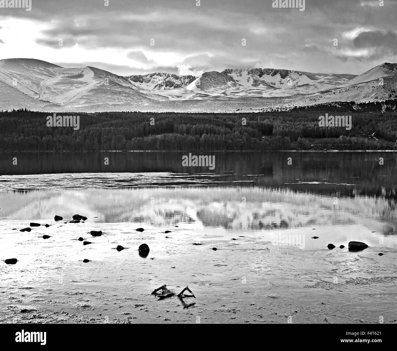 Visualizzazione bianco e nero del Cairngorm plateau si vede attraverso parzialmente congelato Loch Morlich, inverno, Cairngorms, Highlands scozzesi, REGNO UNITO Foto Stock