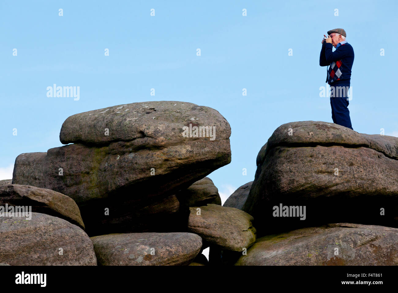 Uomo anziano tenendo ancora sulle rocce vicino Hathersage nel Parco Nazionale di Peak District Derbyshire England Regno Unito Foto Stock