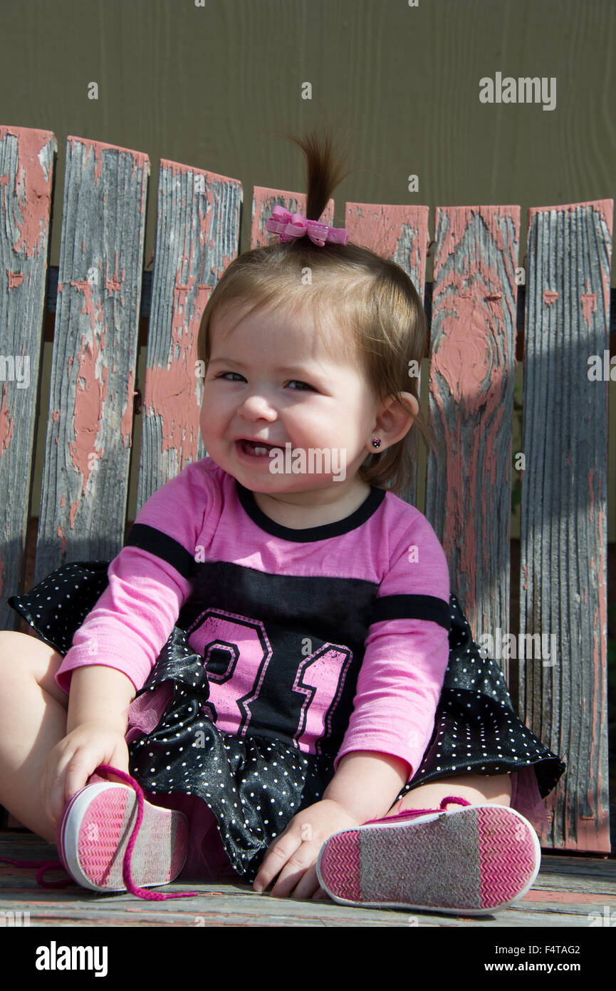 Baby ragazza sorridente seduto su una veranda in legno swing Foto Stock