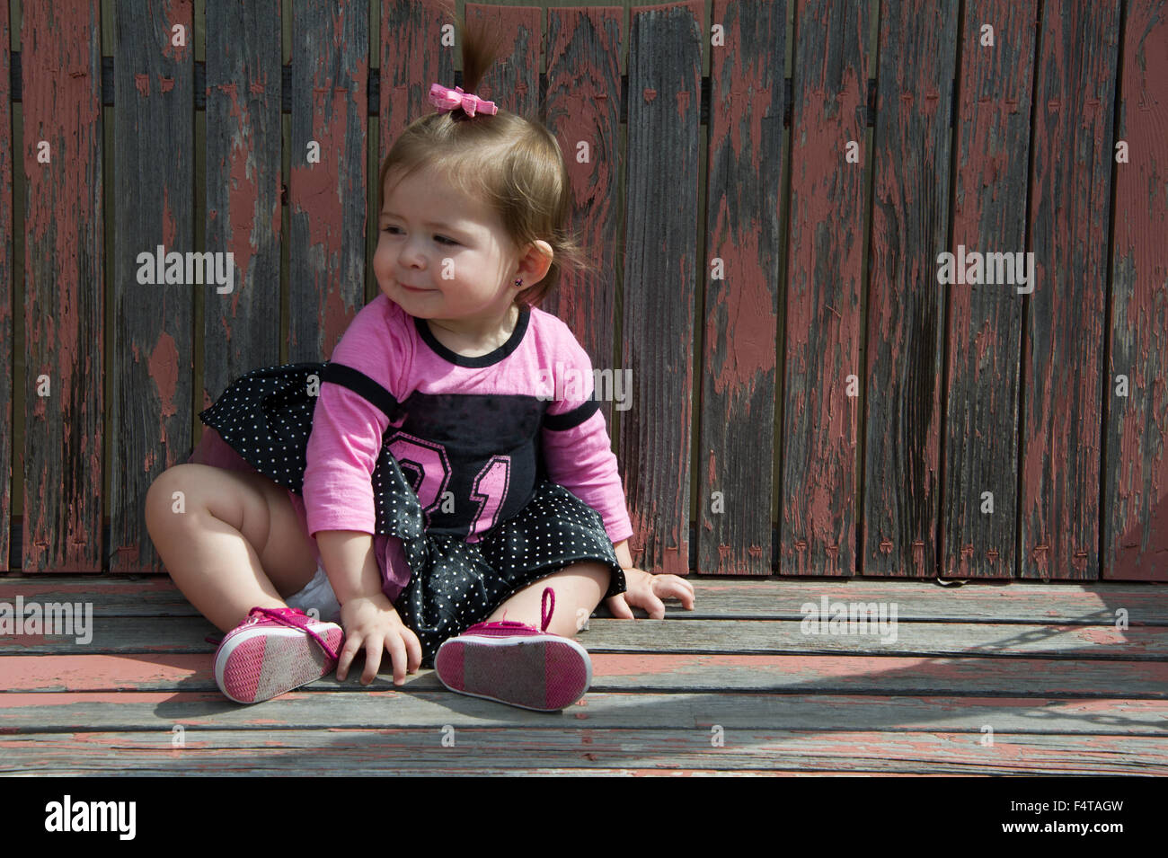 Baby ragazza seduta su una oscillazione di legno Foto Stock