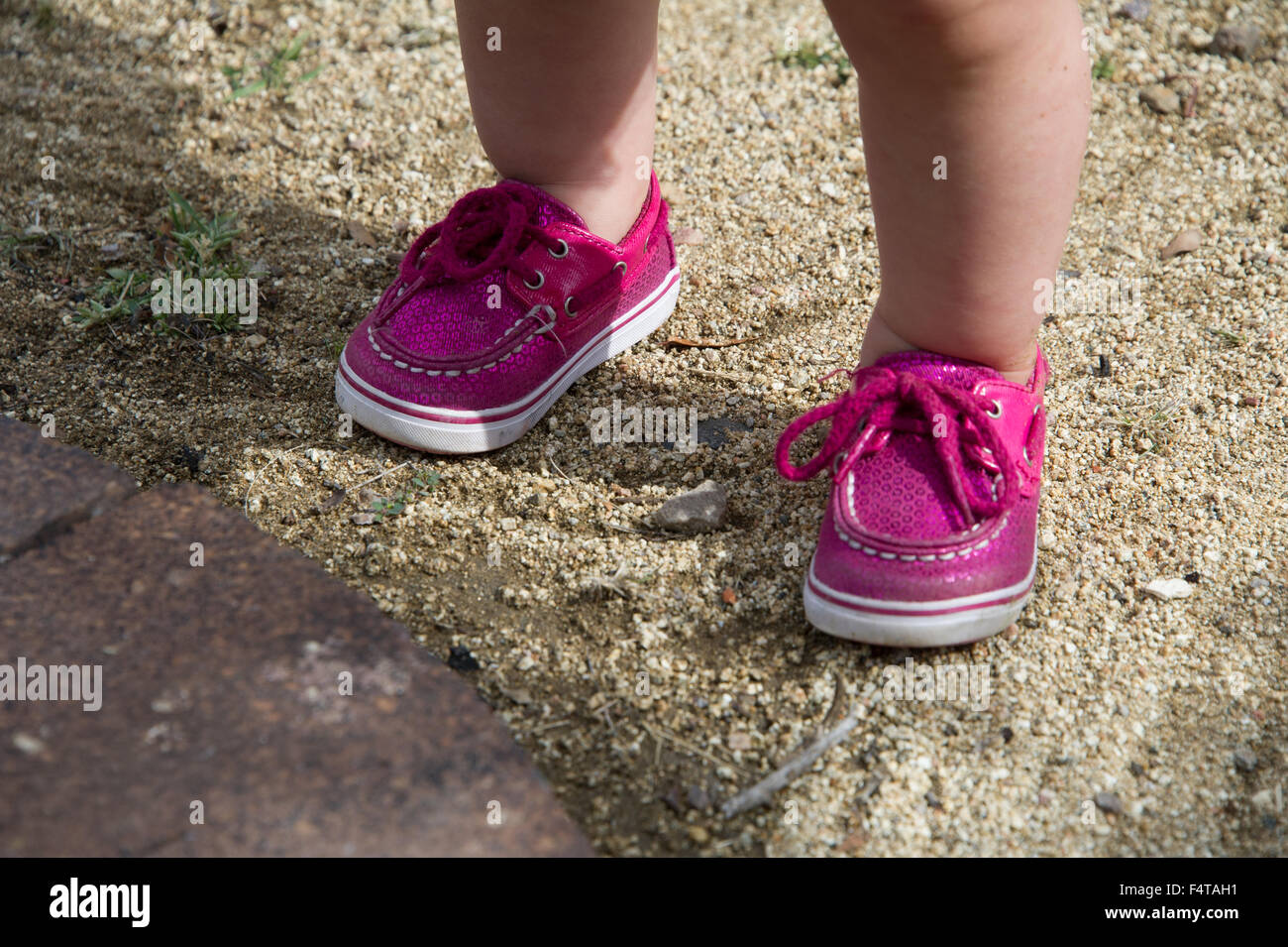 Baby girl in rosa scarpe sulla spiaggia Foto Stock