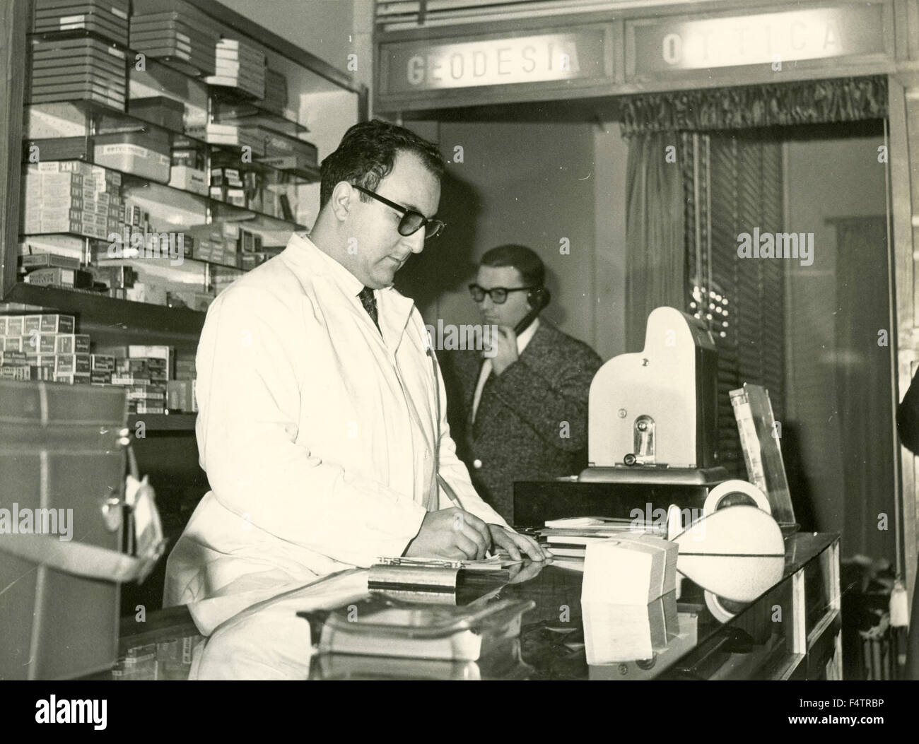 Un venditore in camice bianco dietro il bancone di un ottico del negozio, Italia Foto Stock