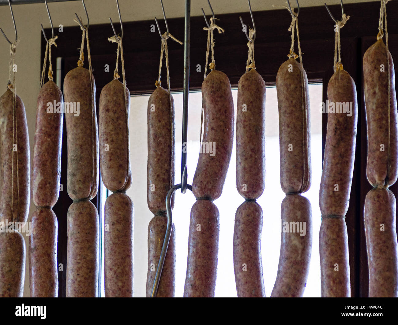 Lunghi filari di carne di maiale, salsicce di appesa in un macellaio toscano Foto Stock