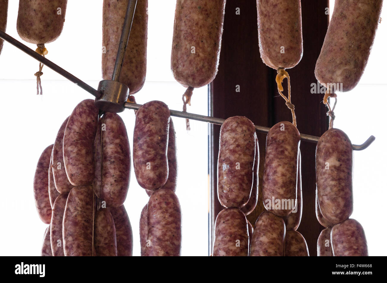 Lunghi filari di carne di maiale, salsicce di appesa in un macellaio toscano Foto Stock