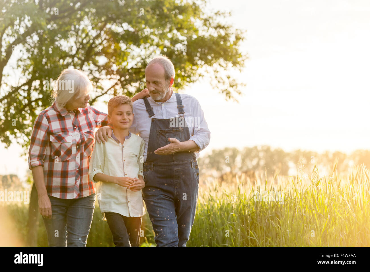 Gli agricoltori nonno e nipote a piedi lungo rurale campo di grano Foto Stock