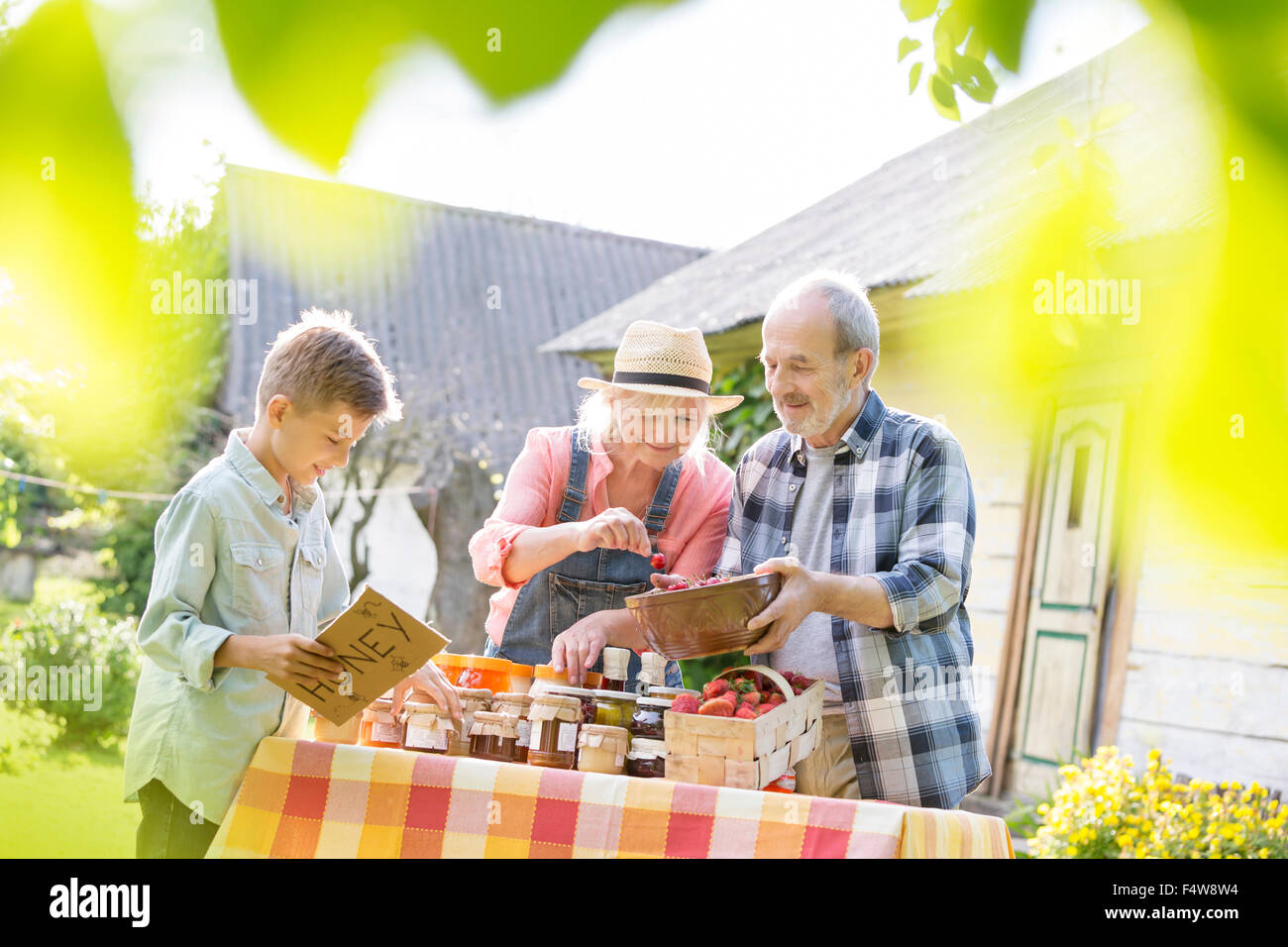 Nonni e nipote di miele di vendita al mercato agricolo in stallo Foto Stock
