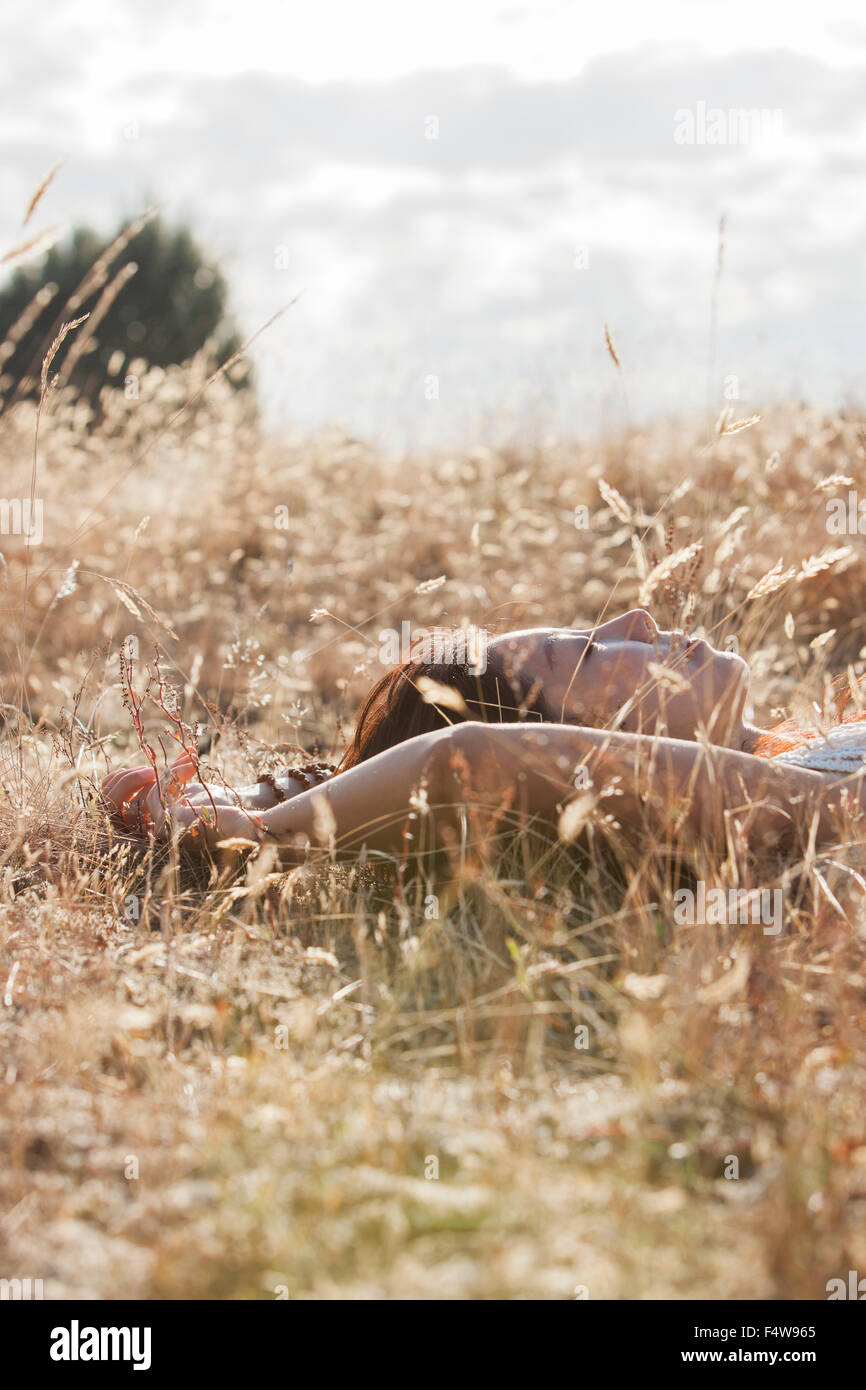 Serena donna che dorme nel soleggiato campo rurale Foto Stock