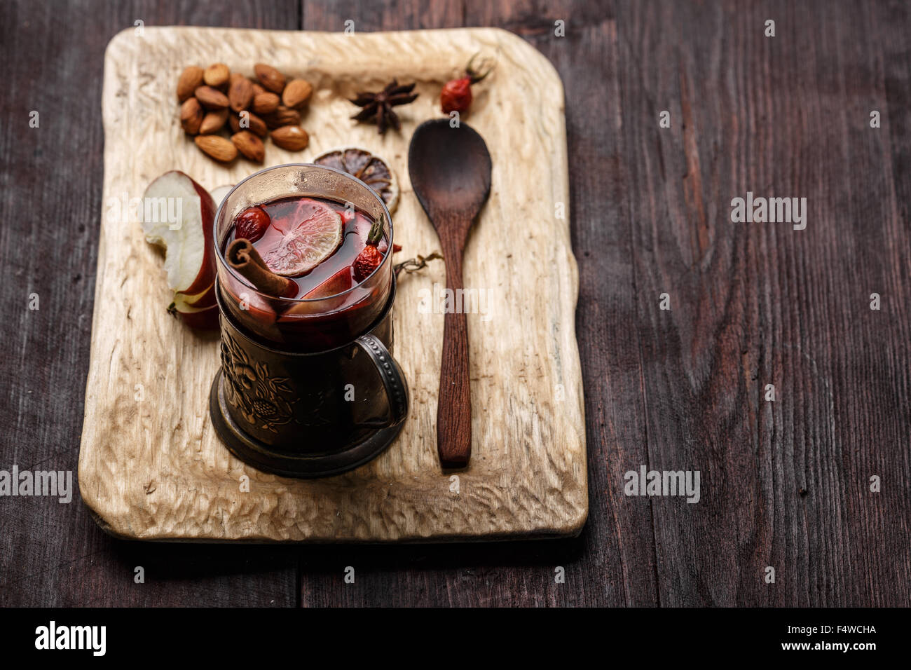 Hot Toddy (vin brulé, punch) con mele e rosa canina servita su legno rustico vassoio con mandorle scure su un tavolo di legno Foto Stock