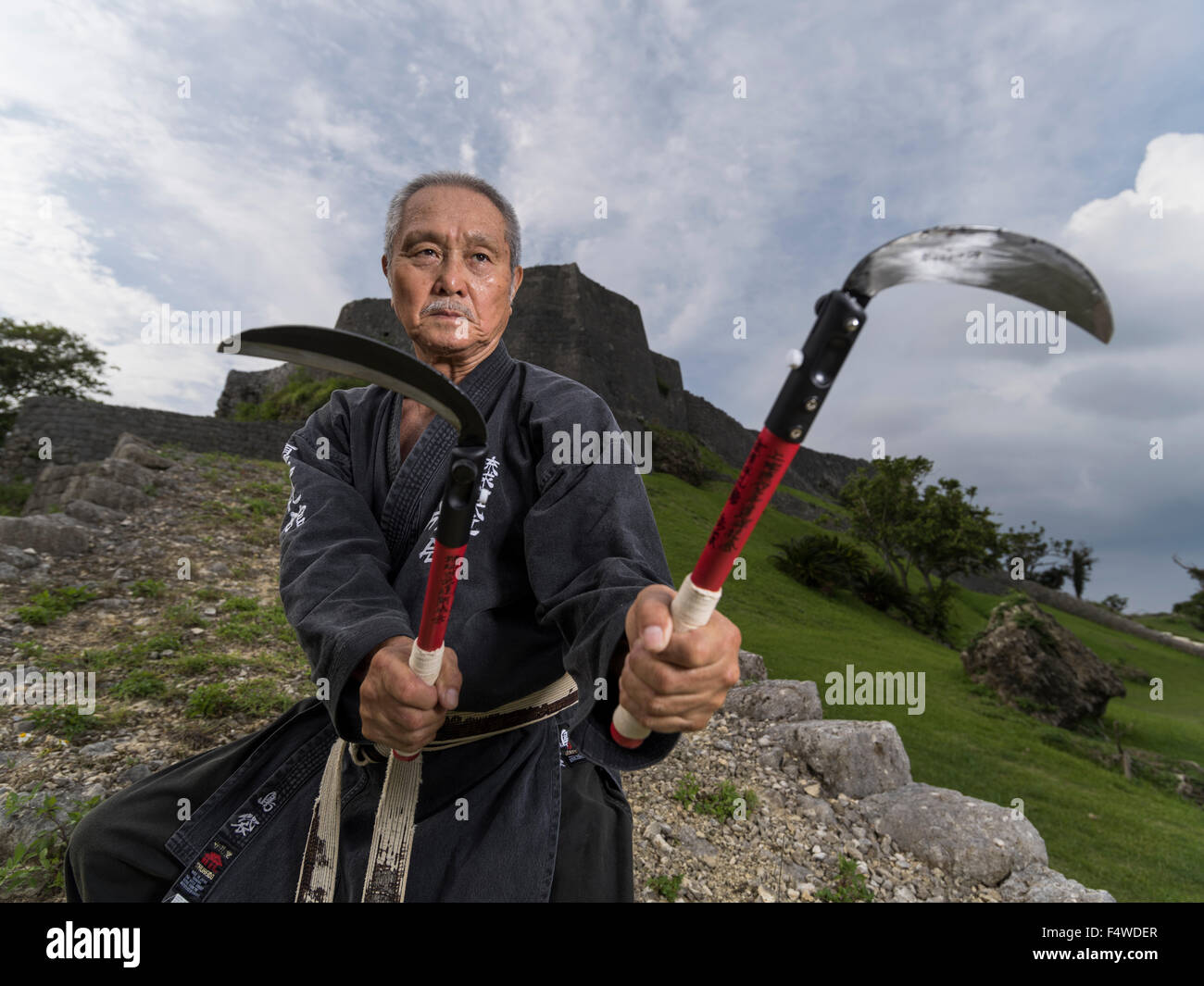 Tsuneo Shimabukuro 島袋 常雄 9th-dan Uechi-ryu Karate, 9th-dan Ryukyu Kobudo training presso il castello di Katsuren Okinawa con la kama Foto Stock