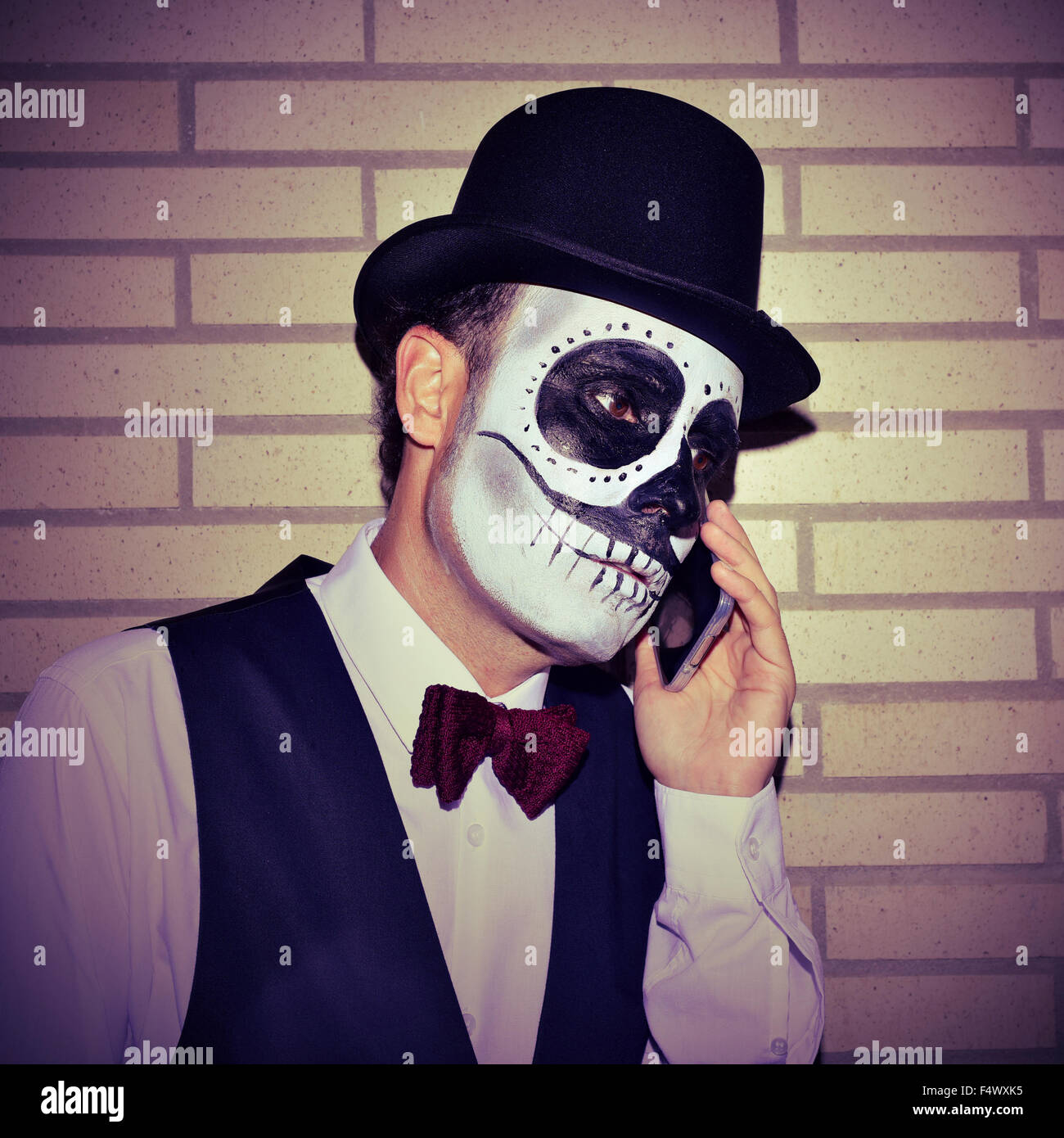 Ritratto di un uomo messicano con calaveras trucco, indossando il filtro  bow tie e top hat sul telefono Foto stock - Alamy