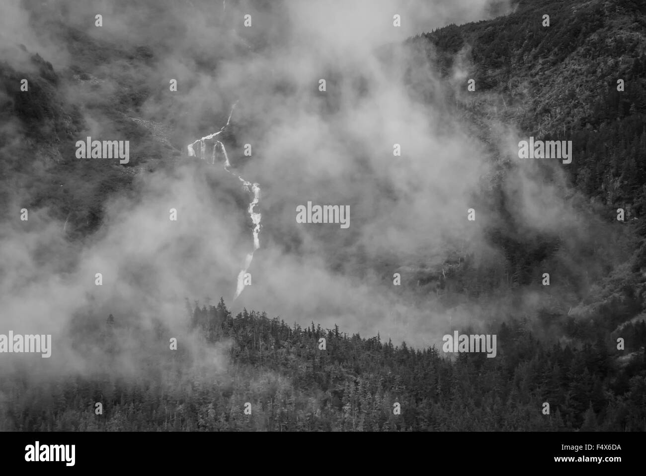 Una scenografica cascata di montagna si blocca verso il basso la scogliera attraverso le nuvole nei pressi di Skagway Alaska | Lynn Canal crociera del fiordo - passaggio interno Foto Stock