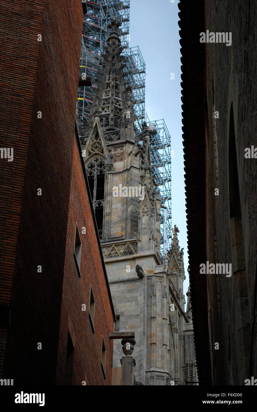 Campanile di una chiesa con un ponteggio visto da una strada stretta tra due vecchi edifici di appartamenti a Madrid. Foto Stock