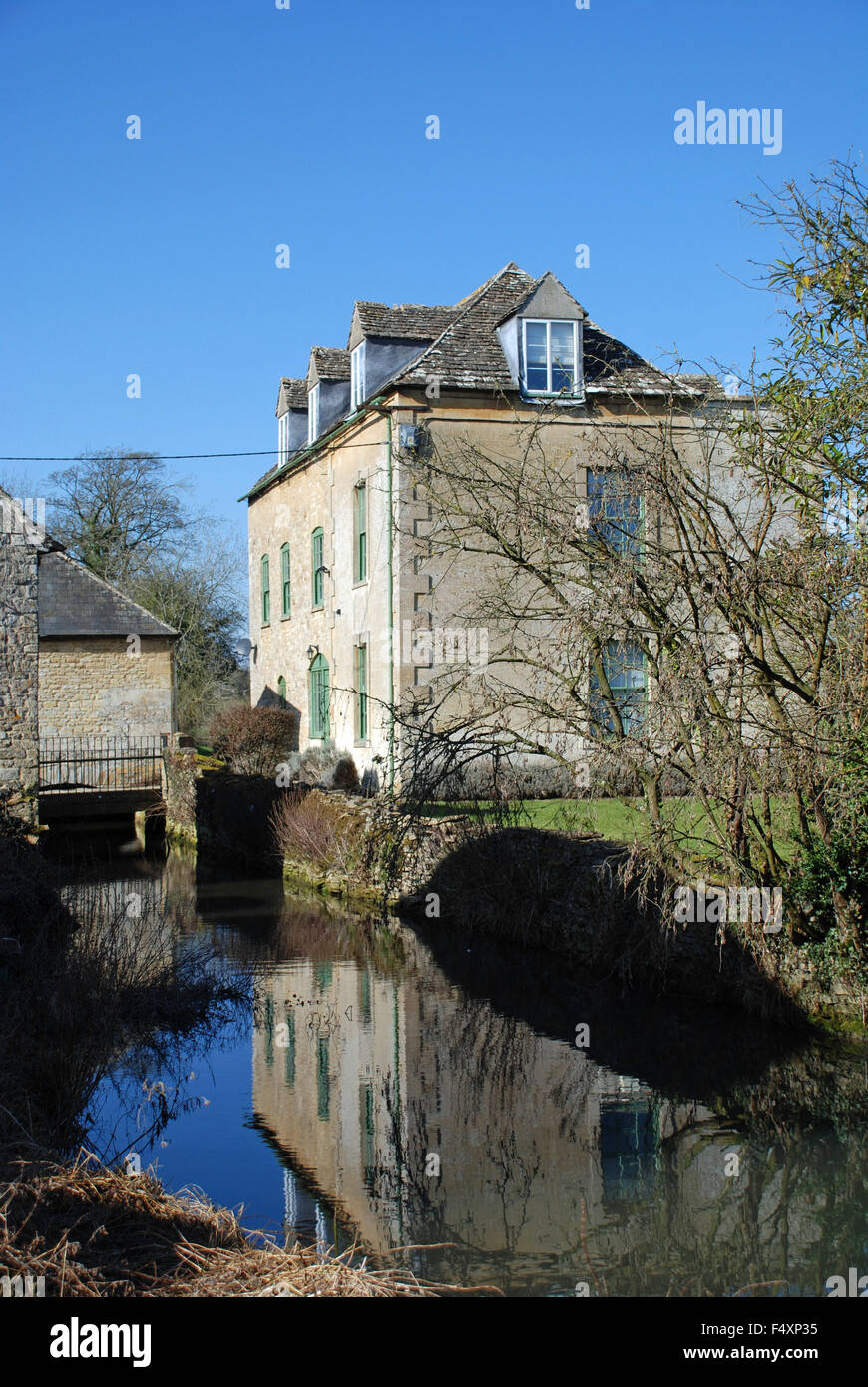 Vecchia casa e acqua simmetria di riflessione a Burford, Oxfordshire, Inghilterra Foto Stock