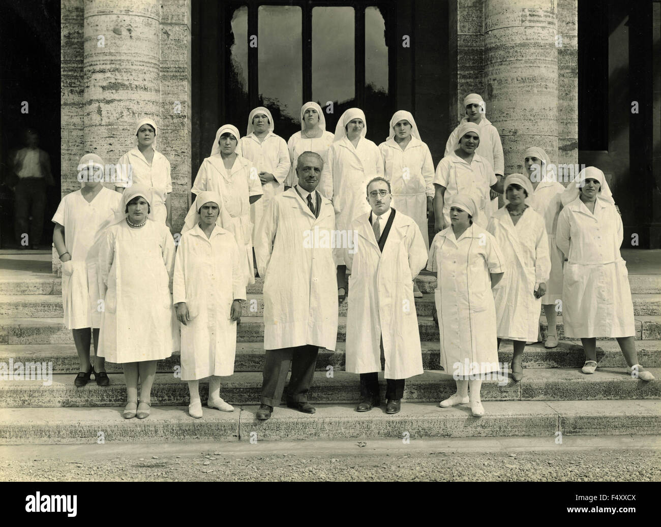 Due medici in camici bianchi con un gruppo di infermieri, Italia Foto Stock