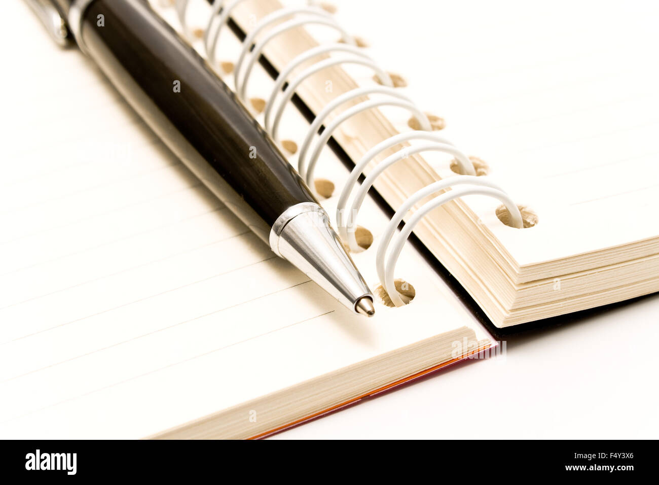 Close-up di penna e agenda a spirale su bianco Foto Stock