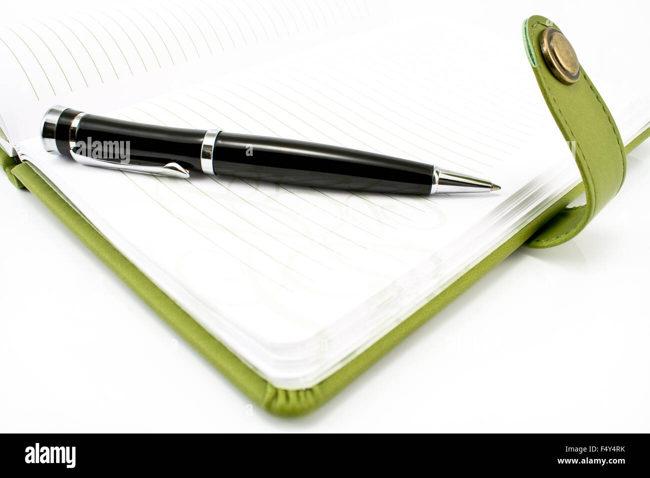 Penna e notebook verde su bianco Foto Stock