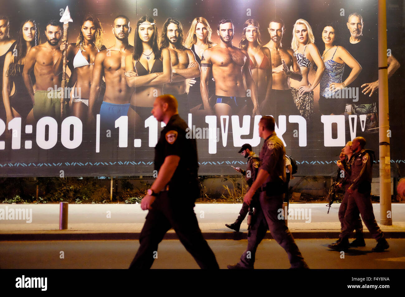La polizia israeliana a piedi passato un enorme cartellone pubblicitario TV israeliana reality show basato sul popolare internazionale formato superstite nel centro di Tel Aviv. Israele Foto Stock