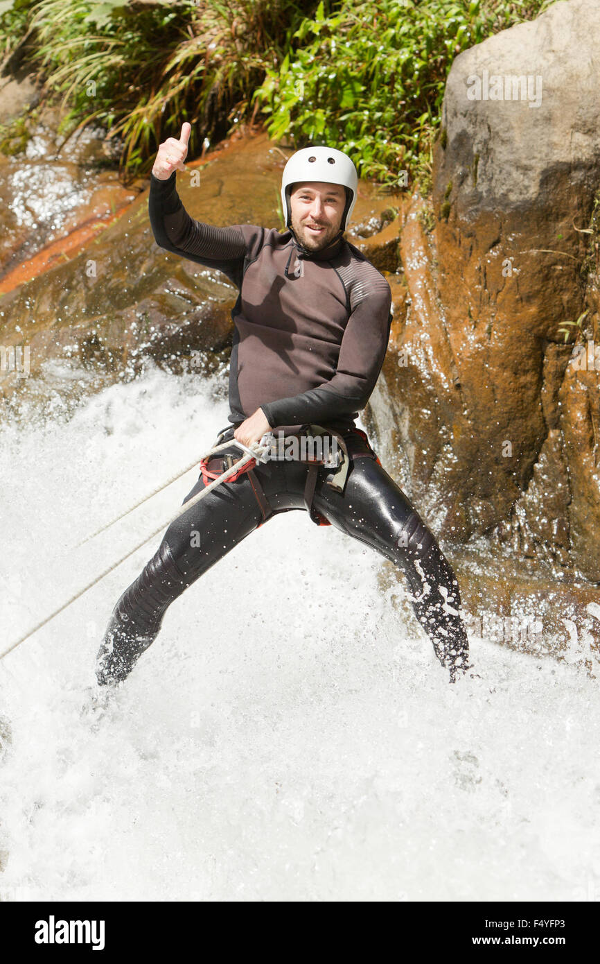 Uomo adulto scendendo una cascata ecuadoriana in una posizione corretta Foto Stock