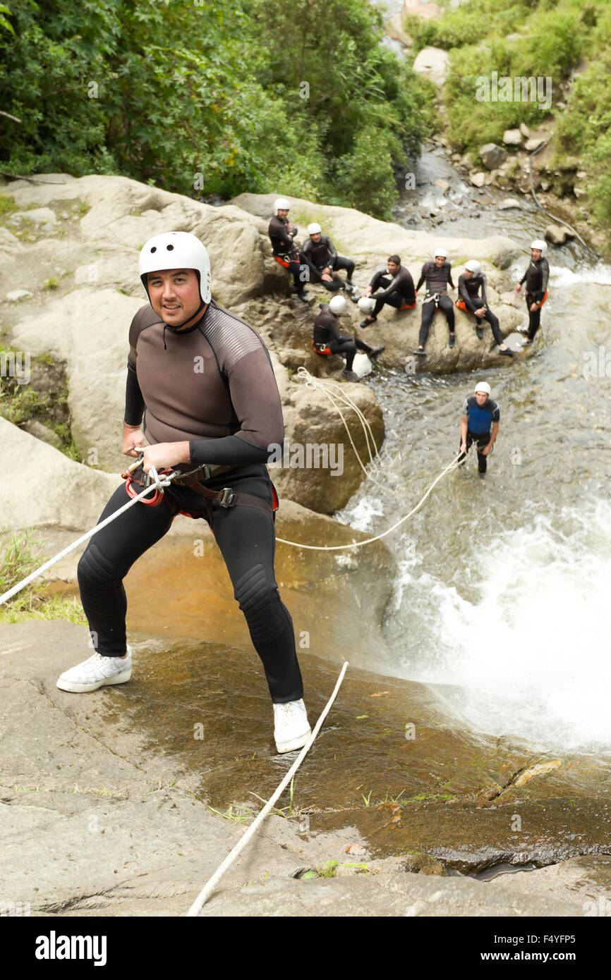 Uomo adulto scendendo una cascata ecuadoriana in una posizione corretta Foto Stock
