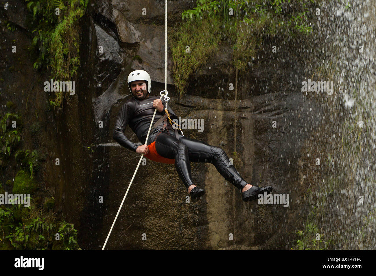 Uomo adulto scendendo una cascata ecuadoriana in una posizione corretta Foto Stock