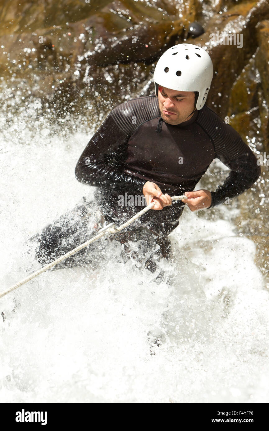 Uomo adulto scendendo una cascata ecuadoriana in una posizione corretta Foto Stock
