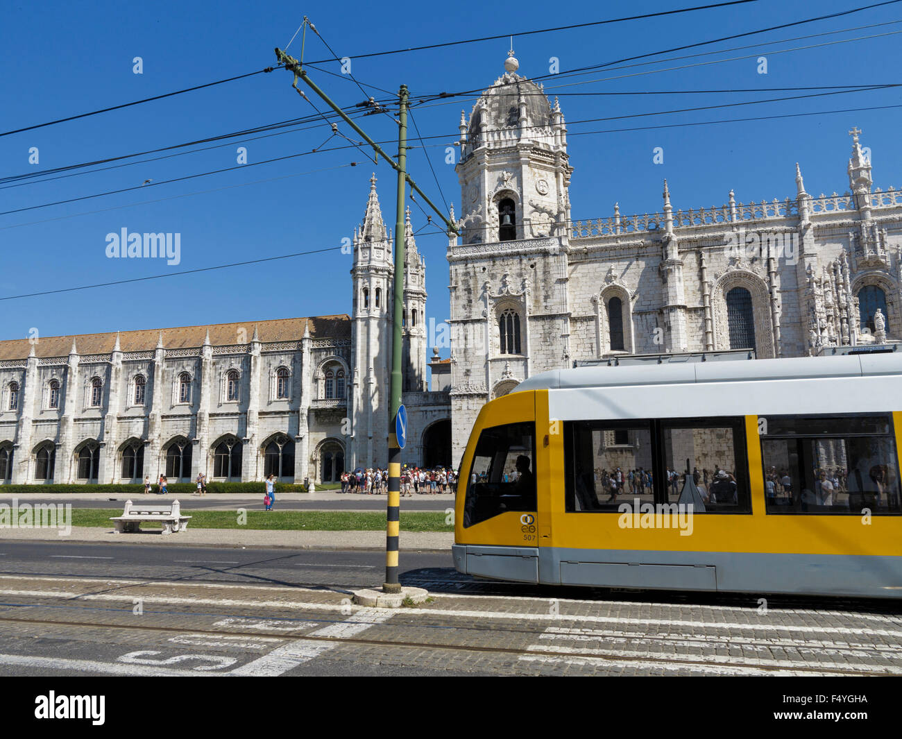 Il giallo il tram che passa nella parte anteriore dei turisti in attesa in linea per visitare la Ger nimos Monastero e chiesa di Santa Maria di Belem Lisbona Portogallo Foto Stock