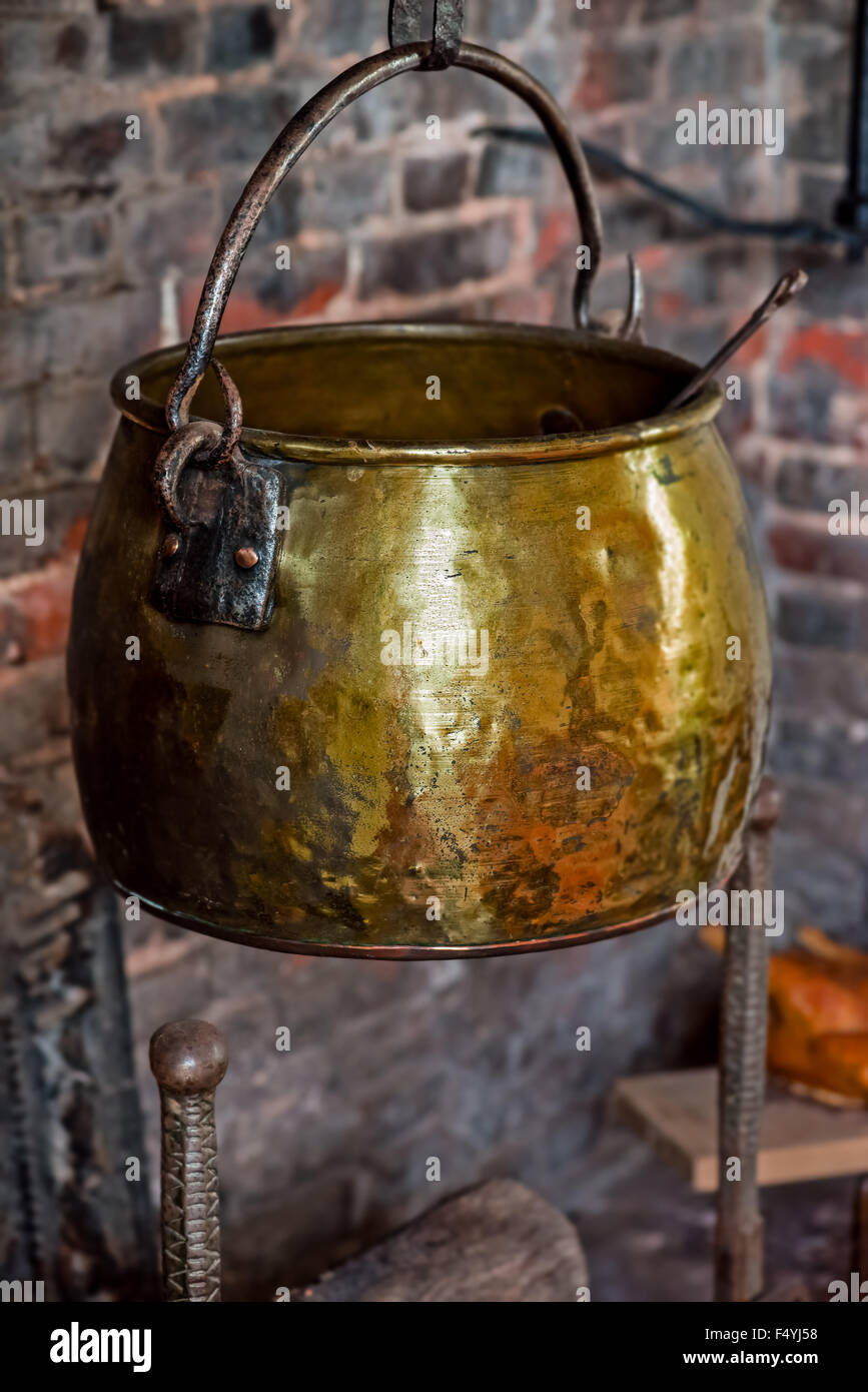 Singola annata antichi 1590 calderone forgiato a mano pentola di cottura hangged dal camino a focolare vecchio golden Foto Stock